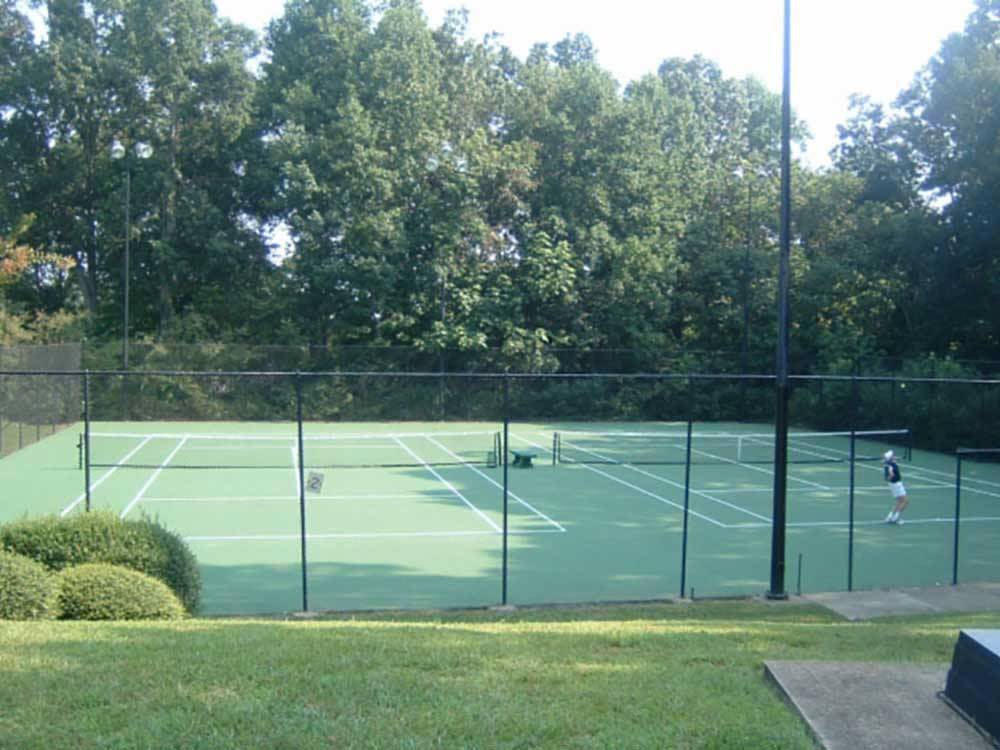 A lone person playing on the tennis courts at OAK HOLLOW FAMILY CAMPGROUND