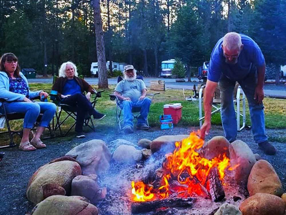 A group of people watching a man move the fire in the fire pit at LONE MOUNTAIN RESORT