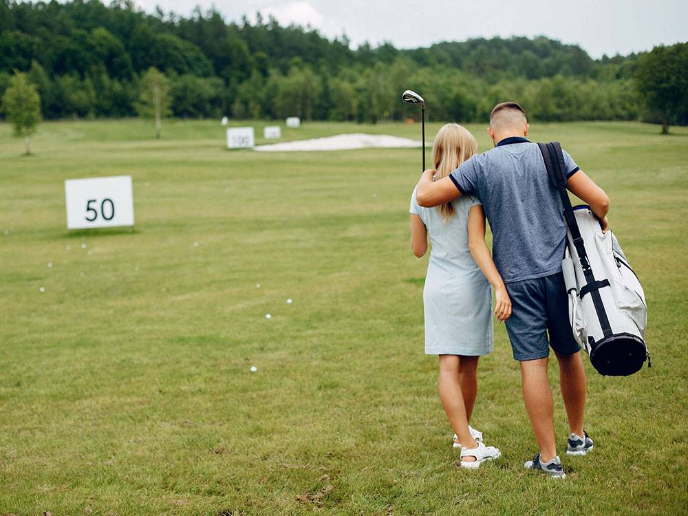 Two people walking on a golf range