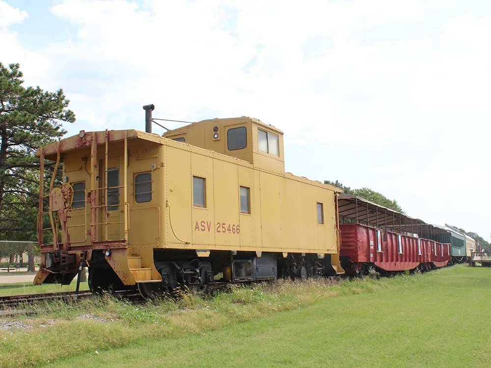 A yellow caboose at the end of a long train at COVERED WAGON RV RESORT