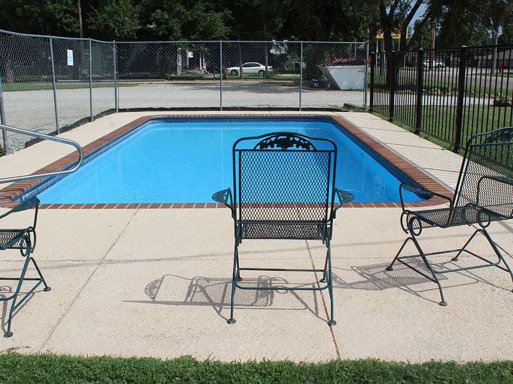 A pool with black wrought-iron chairs at COVERED WAGON RV RESORT