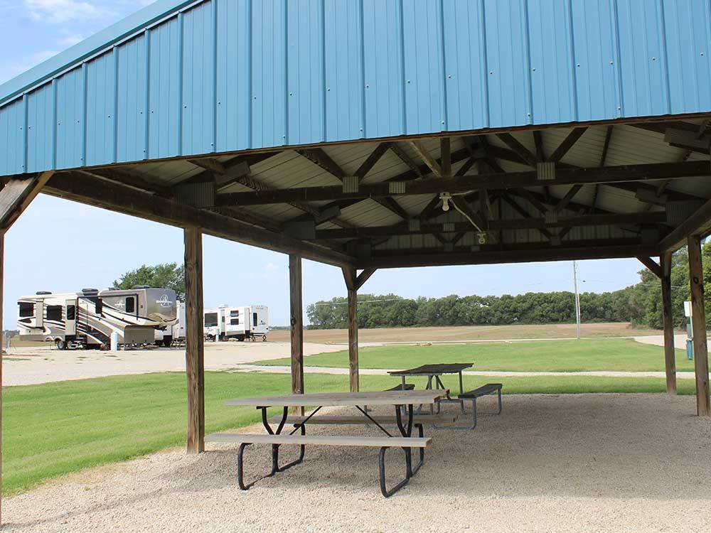 A canopy over picnic tables surrounded by grass at COVERED WAGON RV RESORT