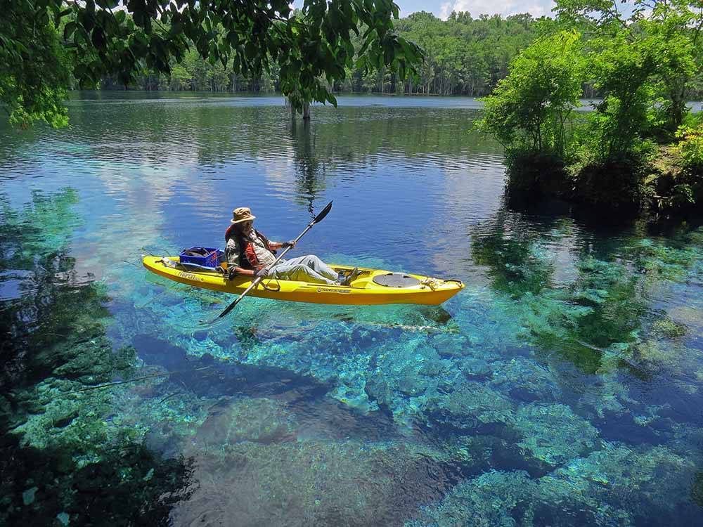 A man using a kayak in crystal blue water at FLORIDA CAVERNS RV RESORT AT MERRITTS MILL POND