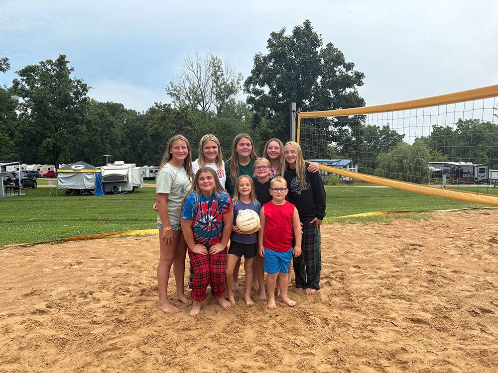 A group of kids on a beach volleyball court