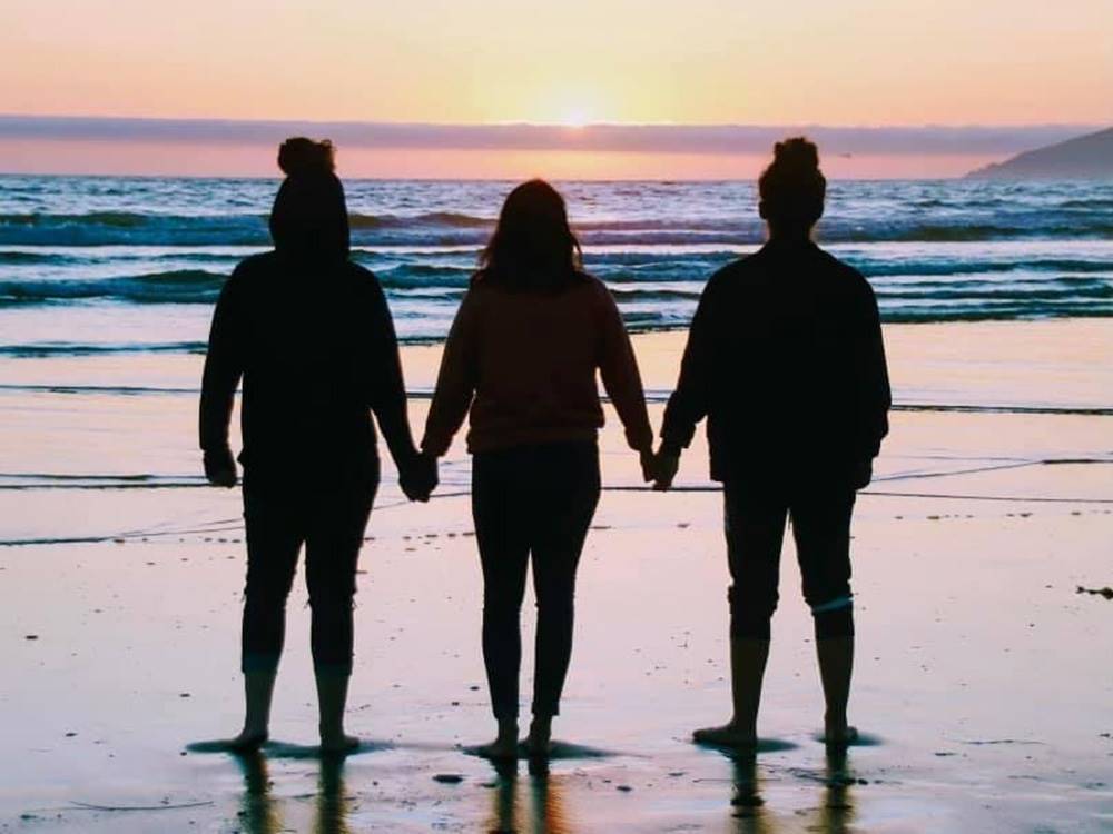 Three people holding hands on the beach