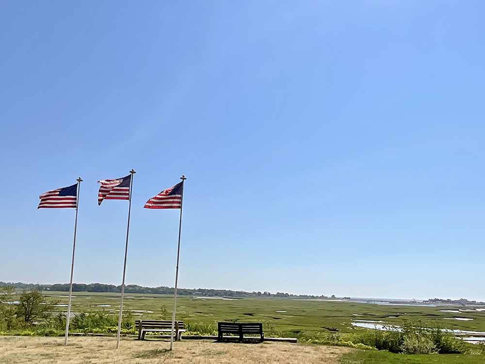 Three American flags flutter over vast landscape at SEA-VU CAMPGROUND