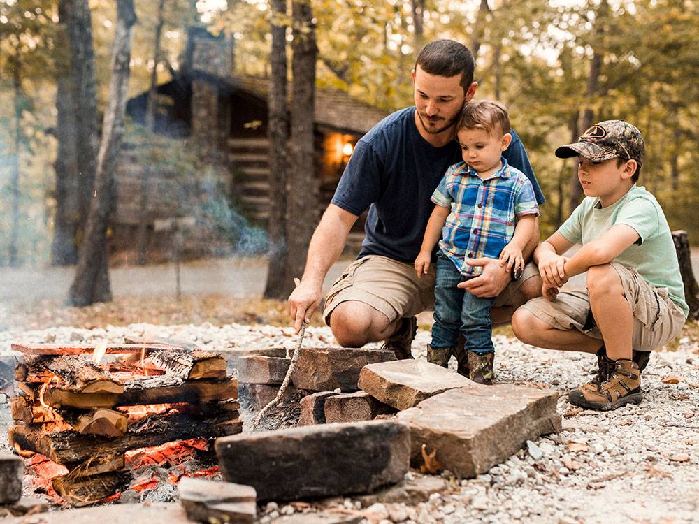 A father stoking a fire with his two boys