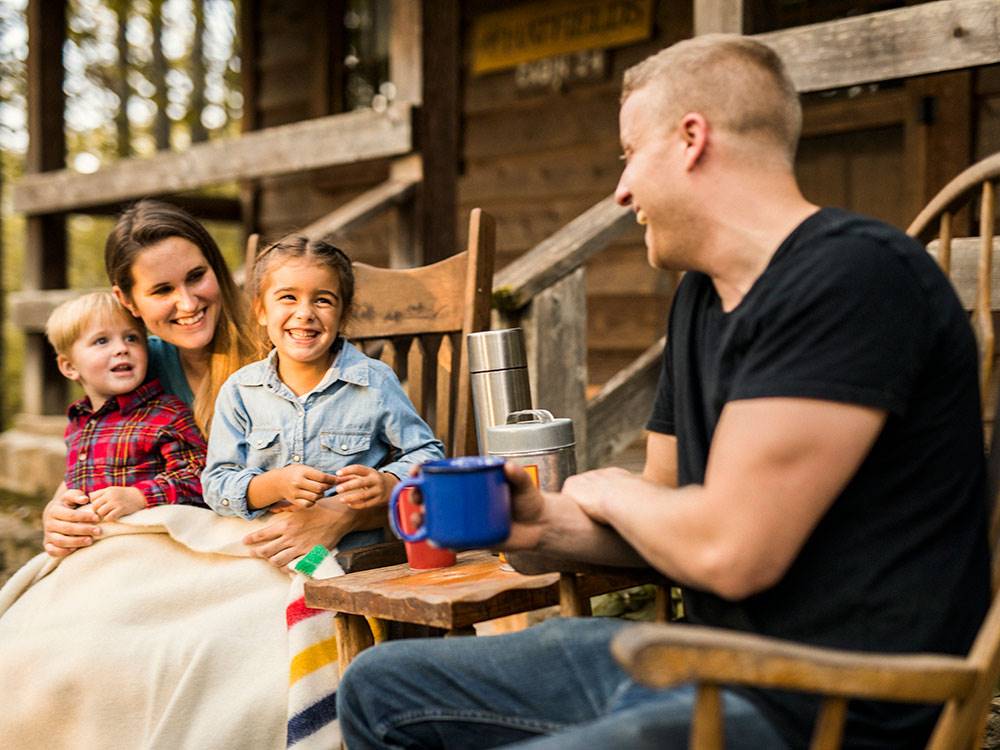 A young family laughing together outside their cabin