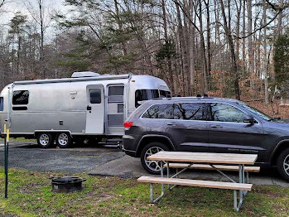 A picnic table next to a car and travel trailer at PRINCE WILLIAM FOREST RV CAMPGROUND