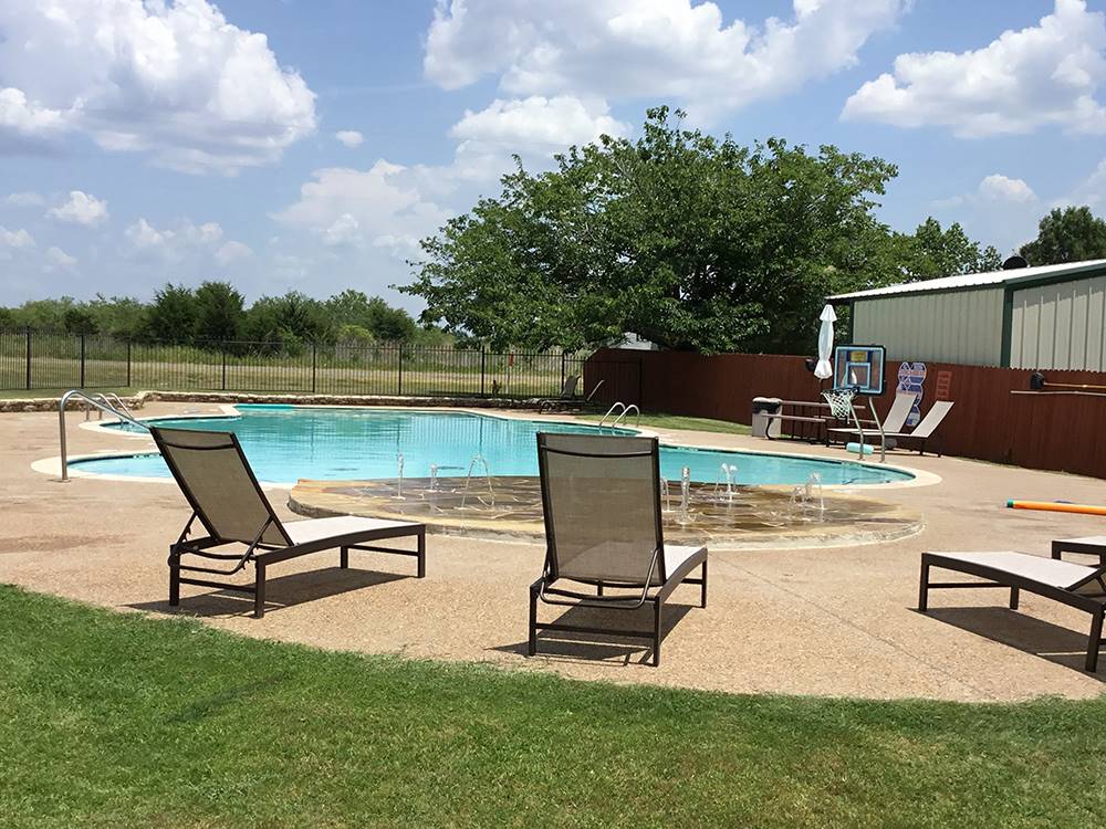 Splash pad and pool with lounge chairs at DALLAS NE CAMPGROUND