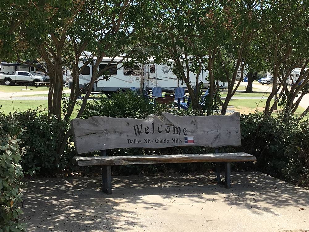 Bench with a welcome greeting and Texas flag at DALLAS NE CAMPGROUND