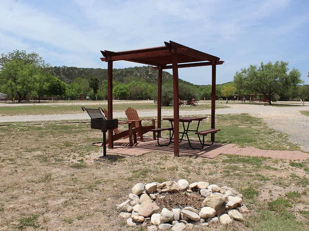 Two chairs and table under a gazebo next to a fire pit at NORTH LLANO RIVER RV PARK