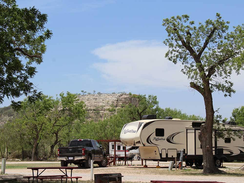 A trailer and truck parked in a gravel site at NORTH LLANO RIVER RV PARK