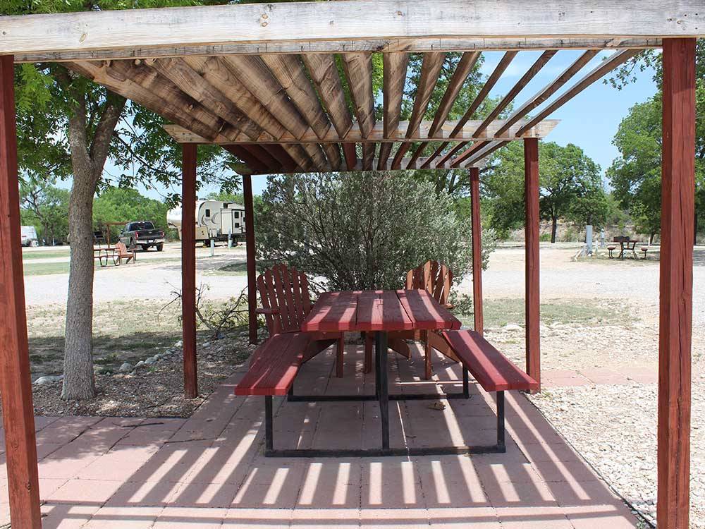 A red table and chairs under a gazebo at NORTH LLANO RIVER RV PARK