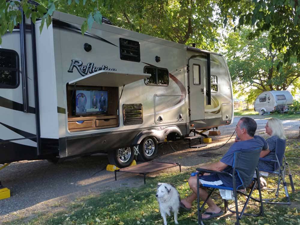 A couple sitting outside their RV watching TV at THE PARKWAY RV RESORT & CAMPGROUND