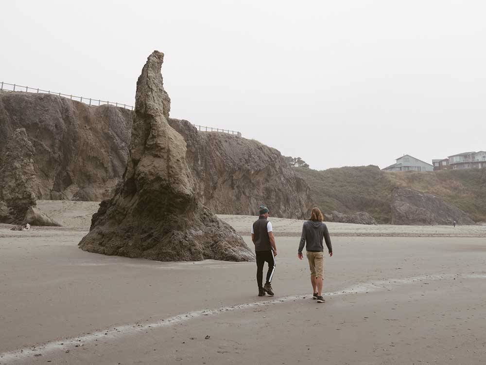 Couple walking on beach near unique rock formation at BANDON RV PARK