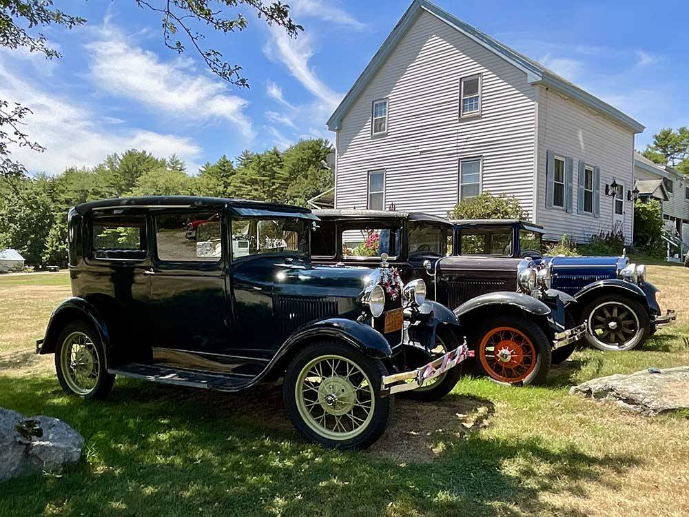 A row of classic cars next to the white building at MEADOWBROOK CAMPING AREA