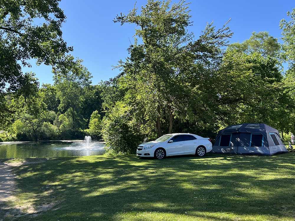 A car and a tent in grass by the water at LANSING COTTONWOOD CAMPGROUND