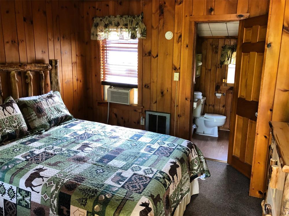 Knotty pine bedroom with in suite bathroom at WHIPPOORWILL MOTEL & CAMPSITES