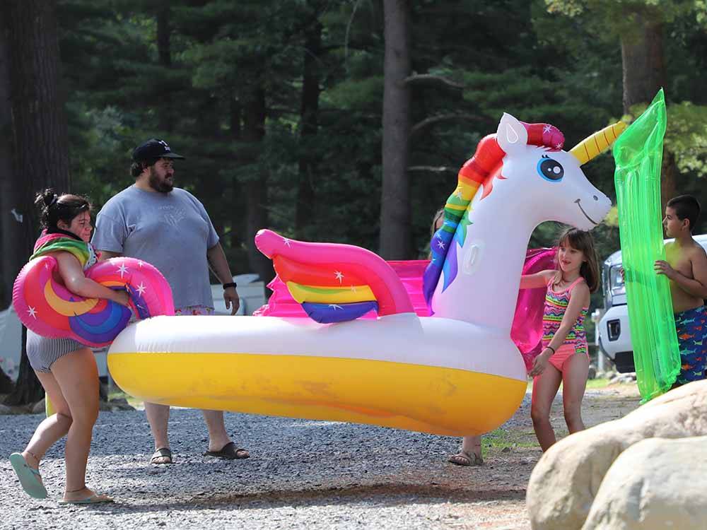 A family holding an inflatable unicorn at LAKE GEORGE RIVERVIEW CAMPGROUND