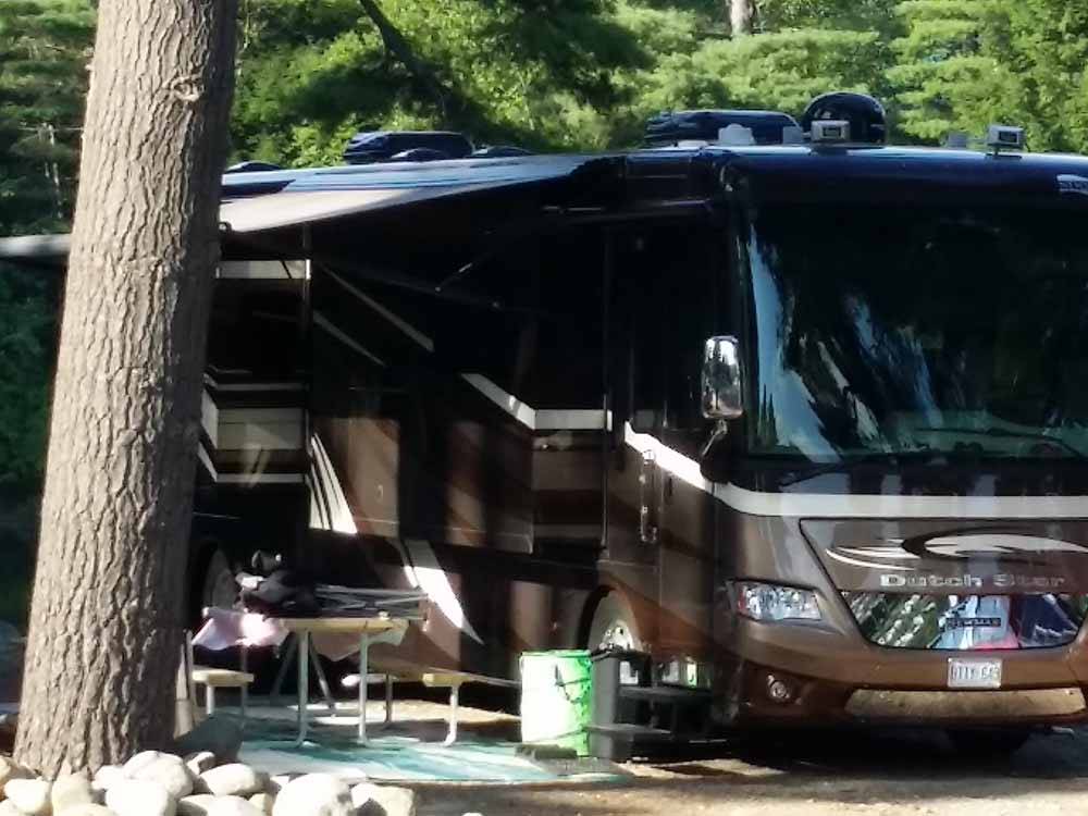 A class A motorhome parked under a tree at LAKE GEORGE RIVERVIEW CAMPGROUND