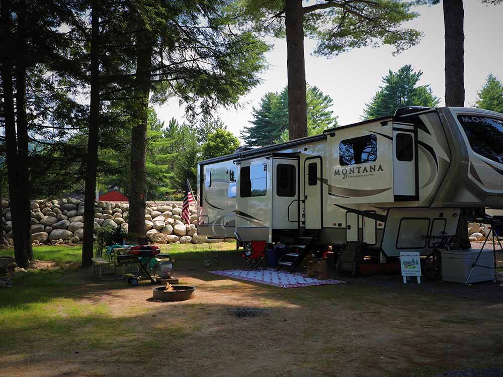 A fifth wheel travel trailer parked under trees at LAKE GEORGE RIVERVIEW CAMPGROUND