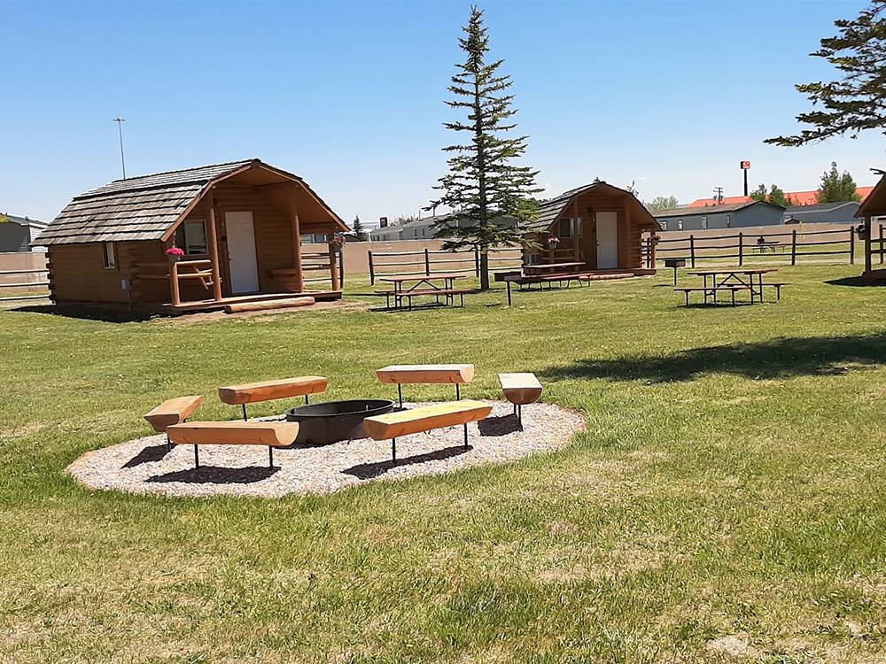 Wooden cabins with picnic benches at LARAMIE RV RESORT BY RJOURNEY