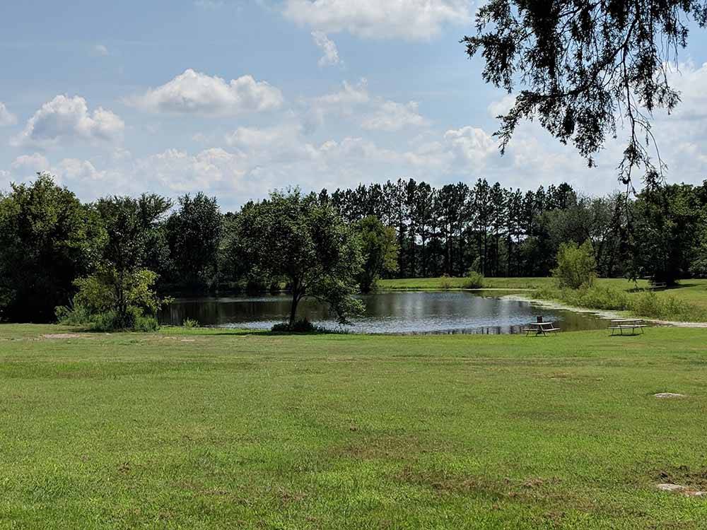 Green field with pond and trees in distance at FORT SMITH-ALMA RV PARK