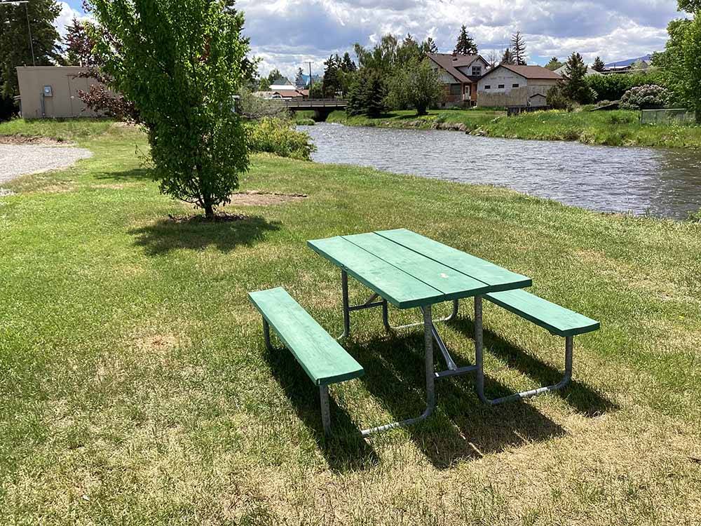 A picnic table by the river at DEER LODGE A-OK CAMPGROUND