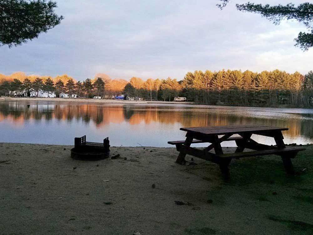 Beach with a picnic table and fire pit at WASSAMKI SPRINGS CAMPGROUND