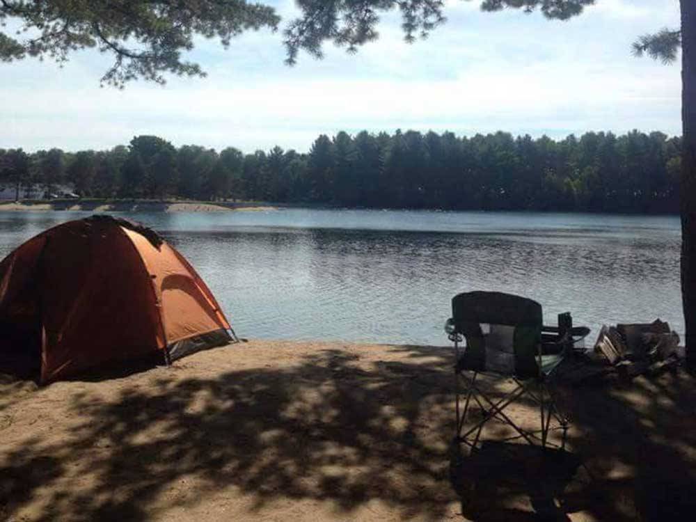 Waterfront tenting site with a chair at WASSAMKI SPRINGS CAMPGROUND