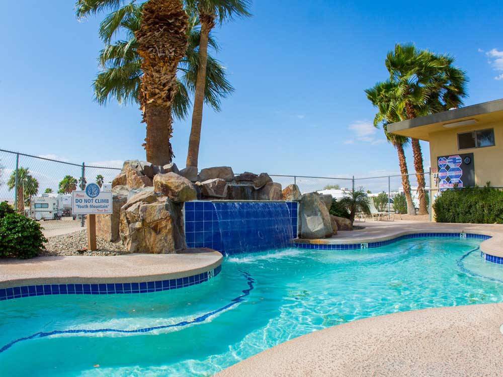 Pool view with rock structure and waterfall at FOUNTAIN OF YOUTH SPA RV RESORT