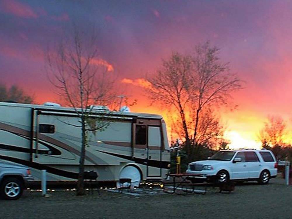 A motorhome and SUV parked at sunset at CORTEZ RV RESORT BY RJOURNEY
