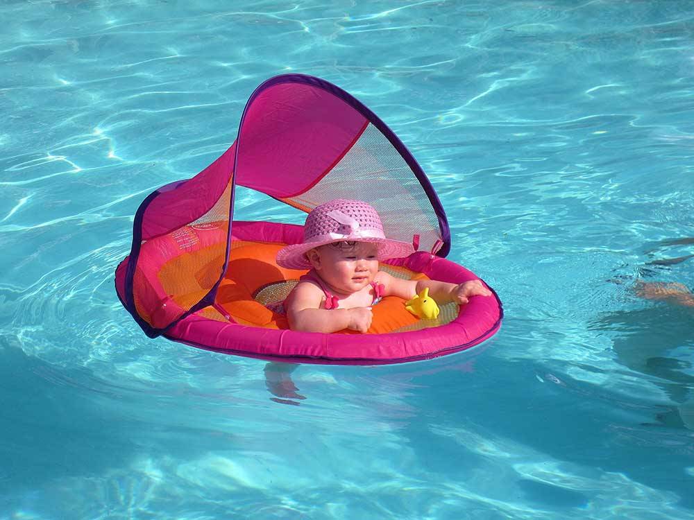 A baby in a floating device in the swimming pool at HATCH RV PARK