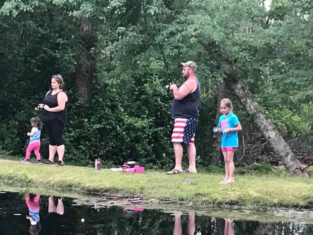 Family fishing on the grassy bank at BUTTERFLY CAMPING RESORT