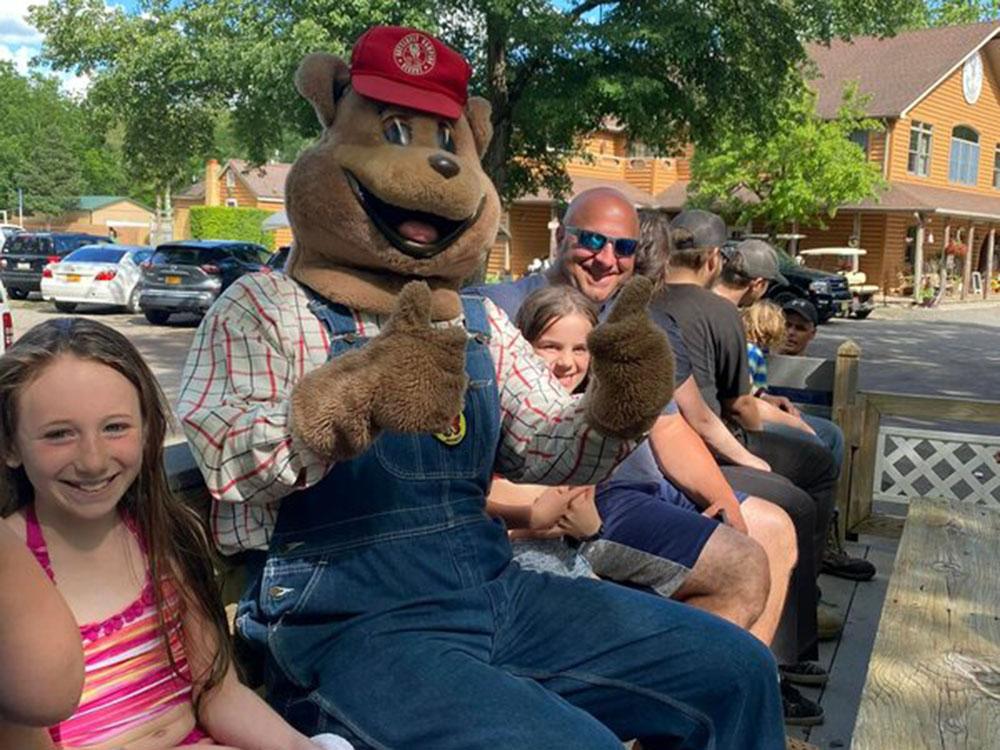 Bear mascot sitting with people on a wagon ride at BUTTERFLY CAMPING RESORT