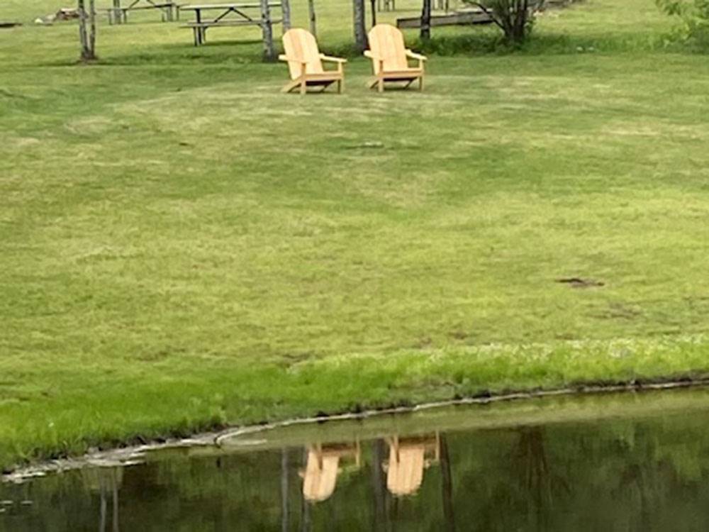 Two wooden Adirondack chairs near the lake