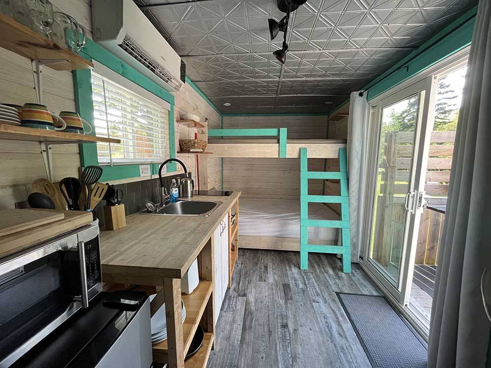 The bunk beds and sliding door of the tiny house at BADDECK CABOT TRAIL CAMPGROUND