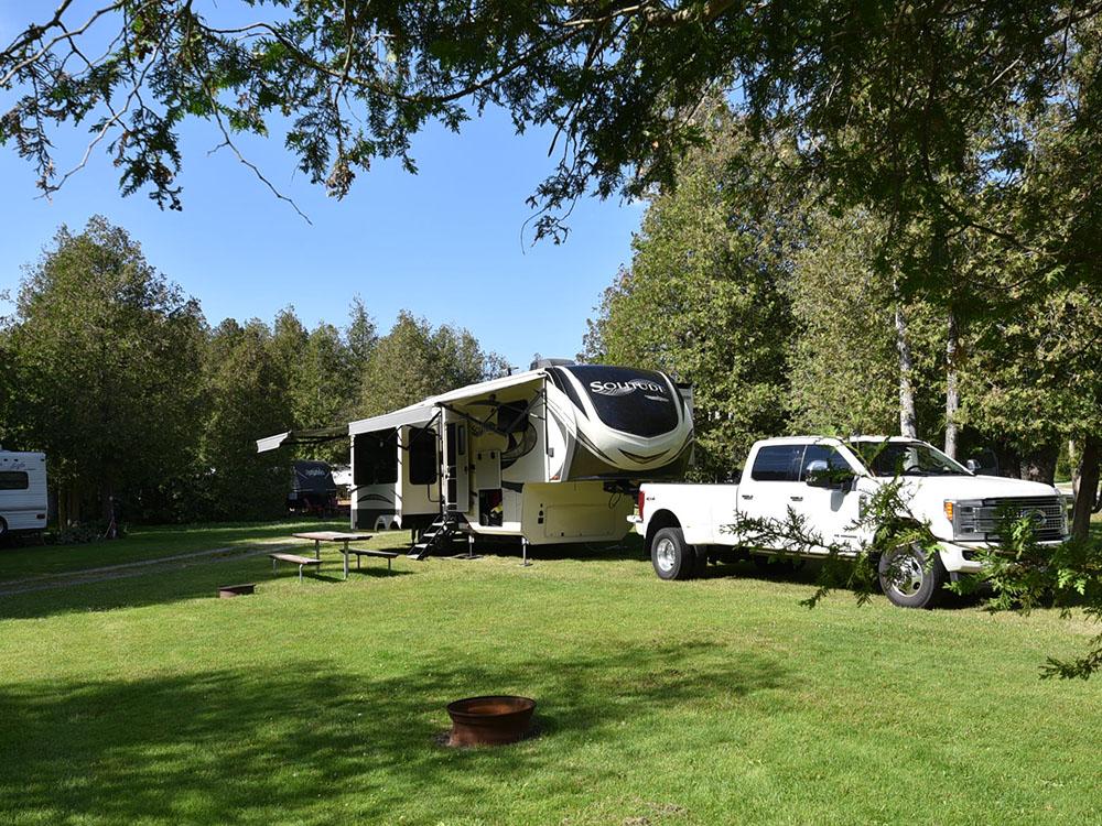 A white truck and a fifth wheel trailer in a site at COBOURG EAST CAMPGROUND