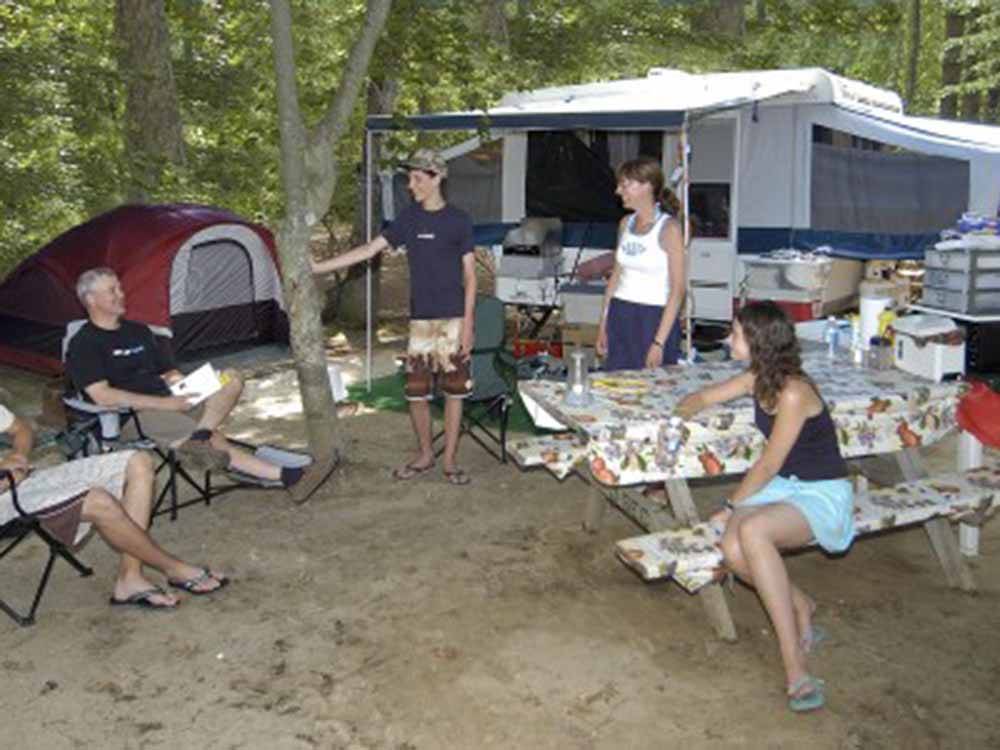 A group of people eating outside of a pop up tent at AVALON CAMPGROUND