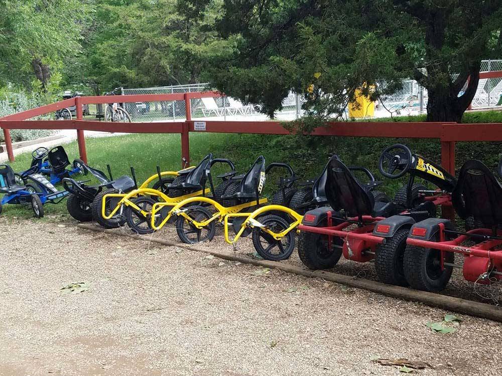 The pedal cars lined up by the fence at BADLANDS / WHITE RIVER KOA HOLIDAY
