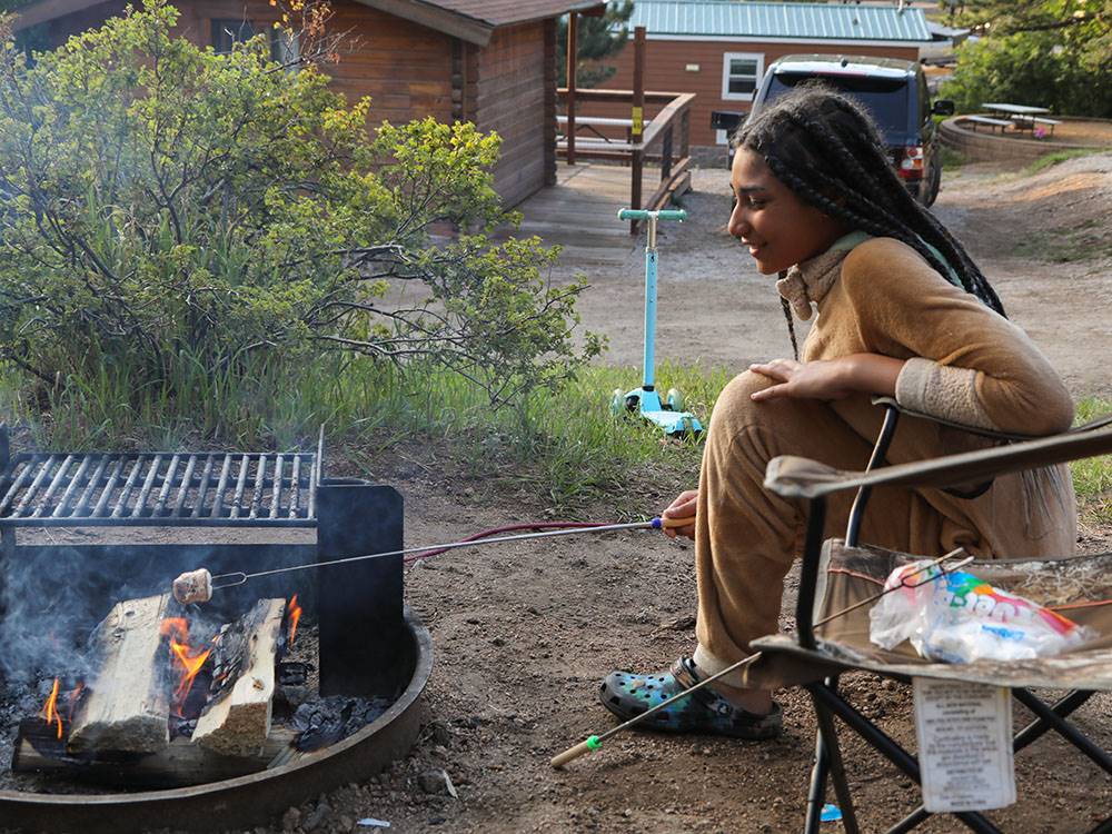 A girl roasting marshmallows at JELLYSTONE PARK ESTES