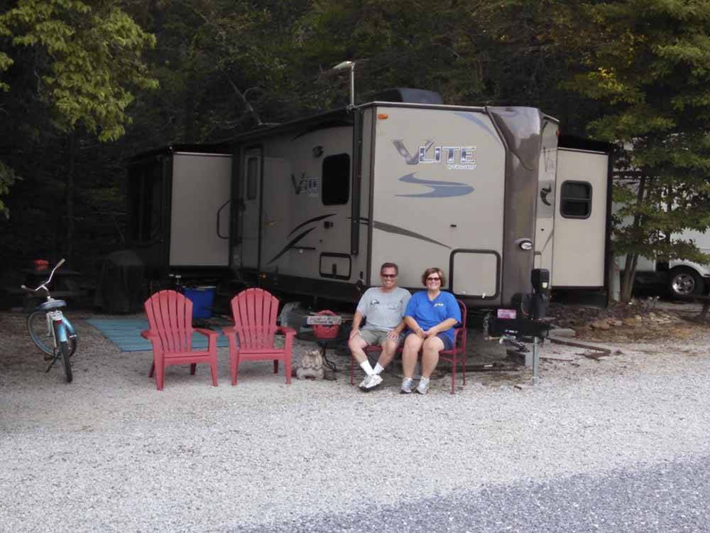 A couple sitting in front of their RV at BUCK CREEK RV PARK