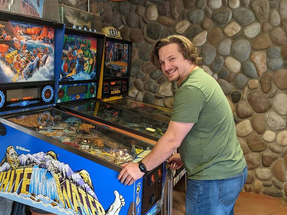 A man playing a pinball game at LONE DUCK CAMPGROUND