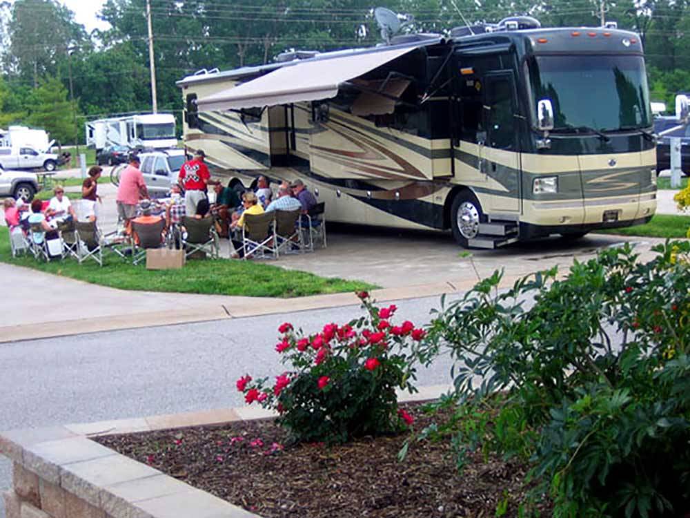 A large group of people sitting next to a motorhome at SUNDERMEIER RV PARK