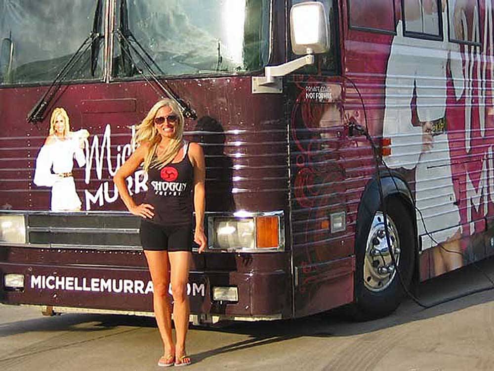 Michelle Murray posing by her bus at SUNDERMEIER RV PARK