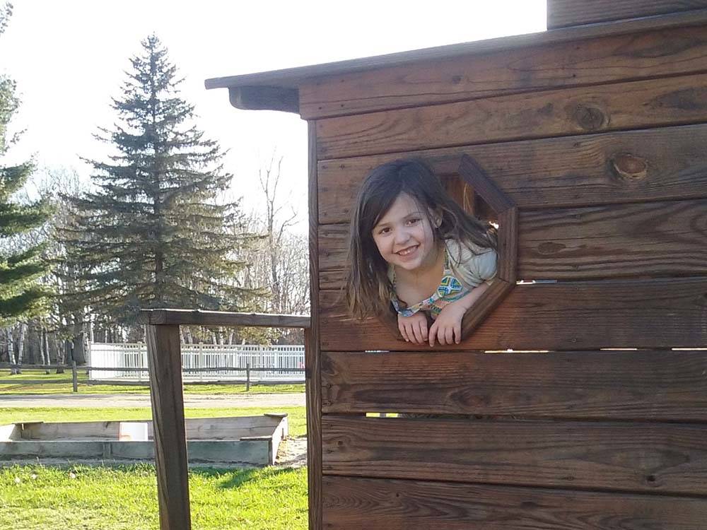 A little girl peeping her head out of a hole at HOUGHTON LAKE TRAVEL PARK CAMPGROUND