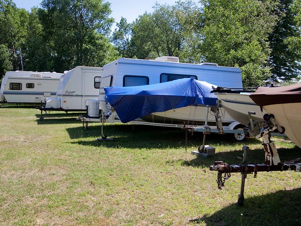 A row of trailers and boats on the grass at HOUGHTON LAKE TRAVEL PARK CAMPGROUND