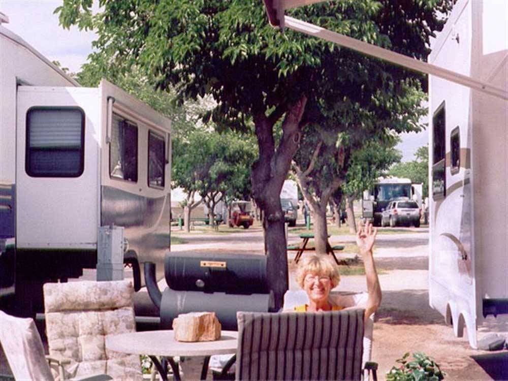 Woman sitting at tables and chairs between motorhomes at MIDLAND/ODESSA RV PARK