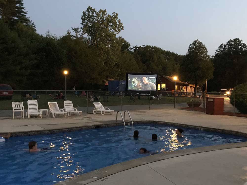Kids in the swimming pool enjoying a movie on a large screen at NATURES CAMPSITES